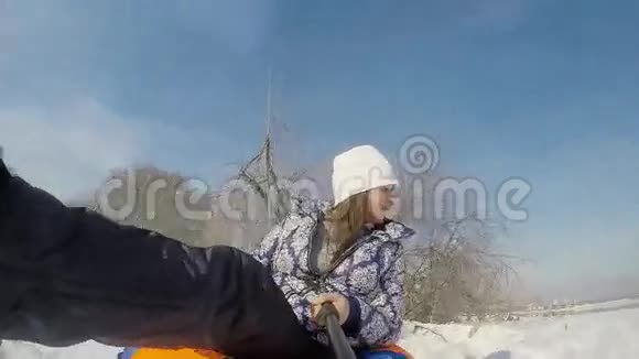 快乐的年轻可爱的女人在冬天阳光明媚的日子里慢慢地在山上滑过太阳并记录下来视频的预览图