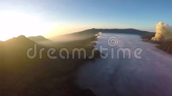在晨雾中飞越CemoroLawang小村庄的空中观景航班视频的预览图