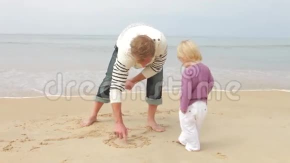 在沙滩上画画的父亲和女儿视频的预览图