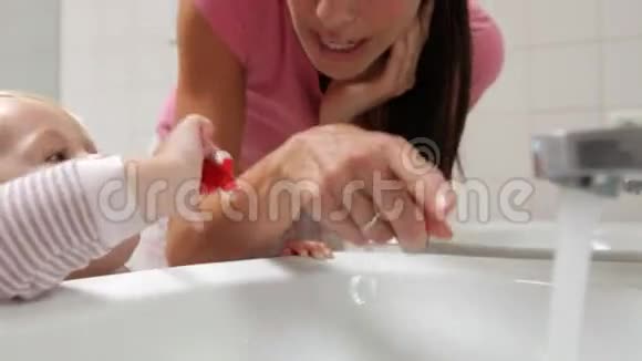 母亲帮助少女在浴室刷牙视频的预览图