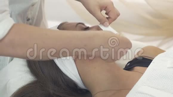 美容师从美容院的少女下巴上取下蜡条视频的预览图
