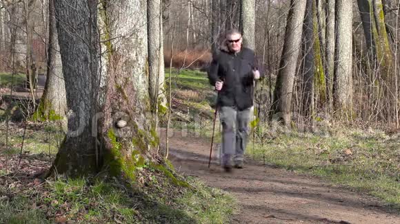 在公园小路上用智能手机拿着手杖的徒步旅行者视频的预览图
