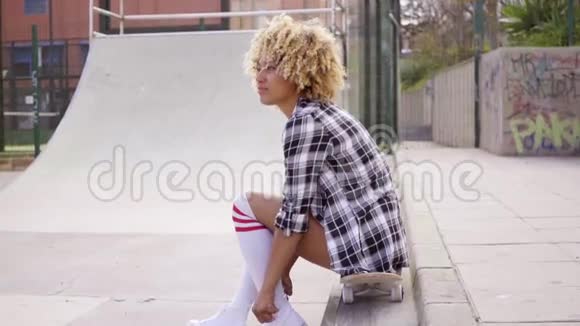 坐在溜冰场滑板上的年轻女子视频的预览图