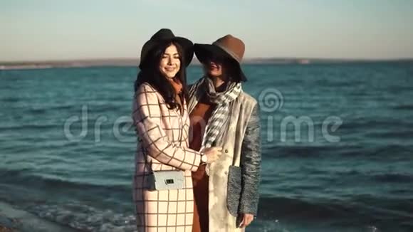 两个可爱的年轻女人正微笑着享受着秋天沿着海洋散步的生活朋友的画像视频的预览图