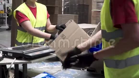 生产工人在出口或出口前将包装好的产品放入纸板箱中的手的特写镜头视频的预览图