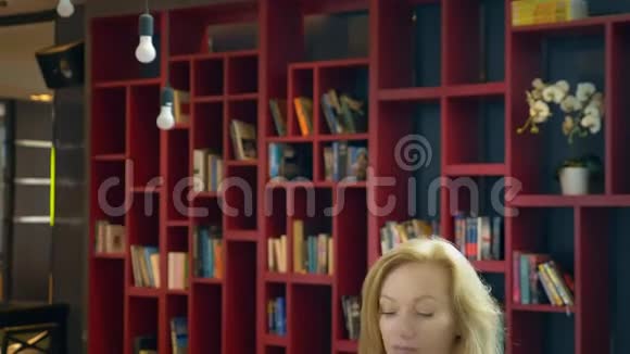 在书架背景下年轻女子在图书馆看书视频的预览图
