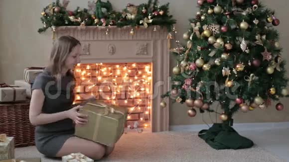 年轻女子把礼物放在圣诞树下视频的预览图