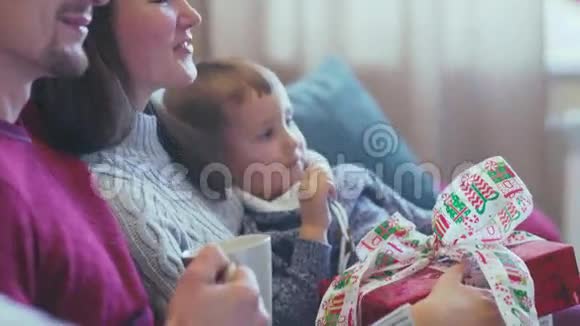 父母和儿子坐在圣诞节室内的沙发上视频的预览图
