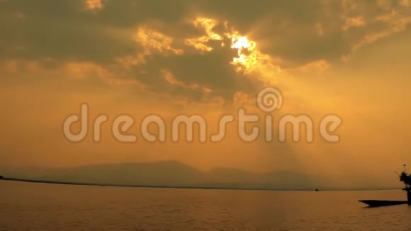 剪影渔夫带着划艇湖面上戏剧性的日落美丽的宁静景象明亮的阳光光芒四射视频的预览图