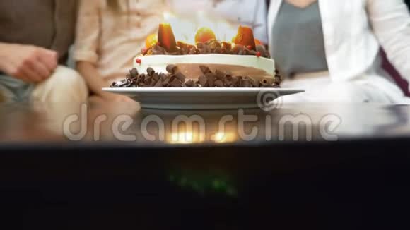 快乐的微笑男孩在她的生日蛋糕上吹蜡烛被家人包围的孩子有蜡烛的生日蛋糕视频的预览图