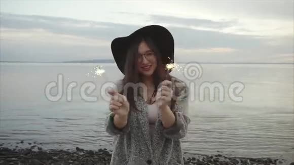 美丽幸福的女人在日落时在海上的海岸上欢腾视频的预览图