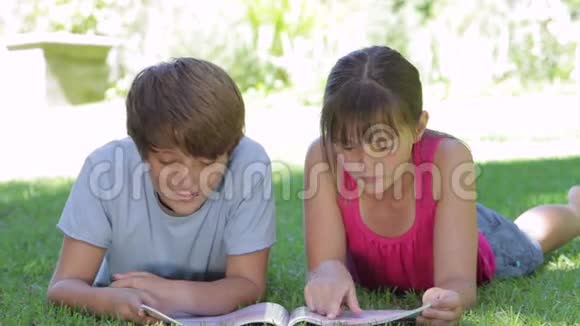 两个孩子一起躺在花园阅读杂志上视频的预览图