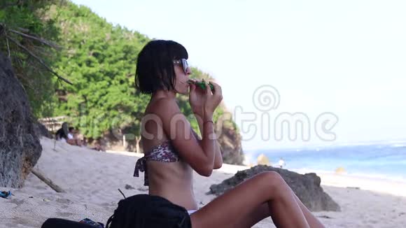 年轻的女人吹着一个绿色的气球年轻的女人在海滩上海洋巴厘岛印度尼西亚视频的预览图