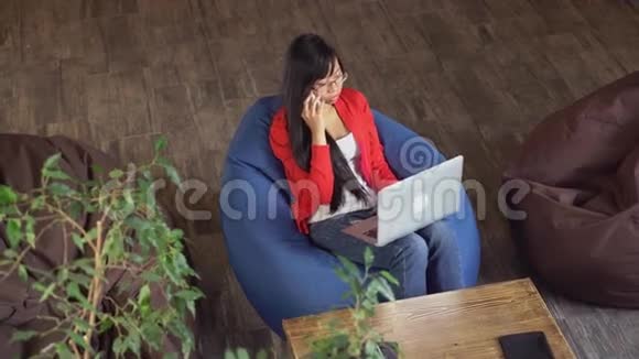 在阁楼工作的亚洲女人坐在豆袋椅子上视频的预览图