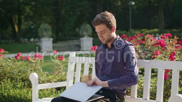 公园里的年轻人用笔记本电脑吃饭视频的预览图