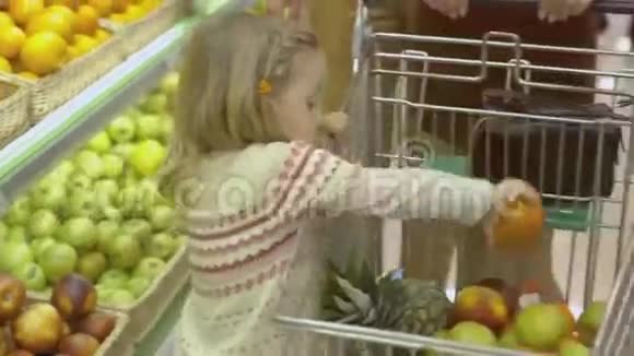 小女孩把水果放进手推车里视频的预览图
