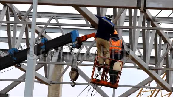 两名工人使用工业电梯在高度焊接金属制品用吊车从驳船向运输船装载煤炭视频的预览图