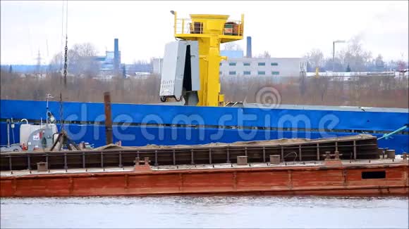 两名工人使用工业电梯在高度焊接金属制品用吊车从驳船向运输船装载煤炭视频的预览图