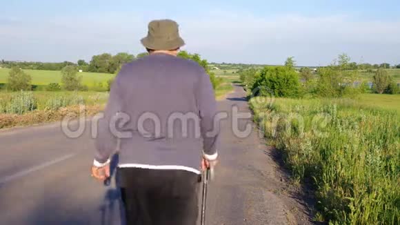 一位手持拐杖的老人在乡间小路上走着视频的预览图