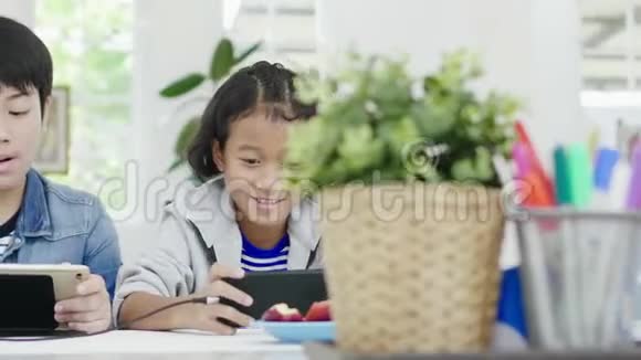 可爱的小女孩和小男孩在智能手机和平板电脑上玩竞争性电子游戏视频的预览图