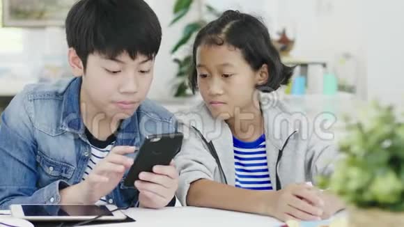 可爱的小女孩和小男孩在智能手机和平板电脑上玩竞争性电子游戏视频的预览图