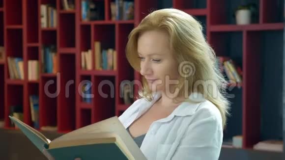 在书架背景下年轻女子在图书馆看书视频的预览图