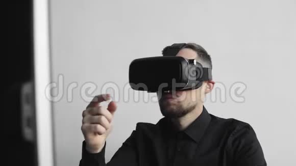 坐在电脑旁戴着虚拟现实眼镜试图触摸一些东西或点击一些东西的小胡子男人视频的预览图