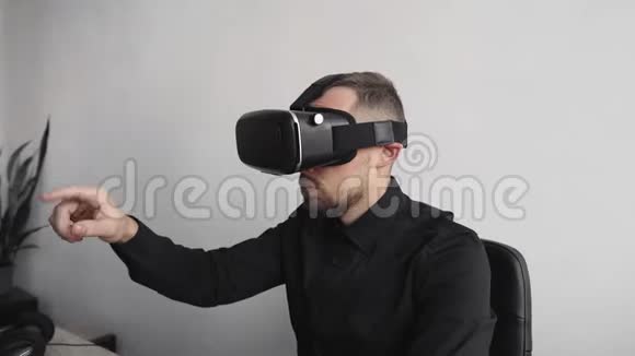 坐在电脑旁戴着虚拟现实眼镜试图触摸一些东西或点击一些东西的小胡子男人视频的预览图