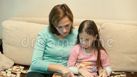 妈妈和女儿坐在沙发上看书视频的预览图