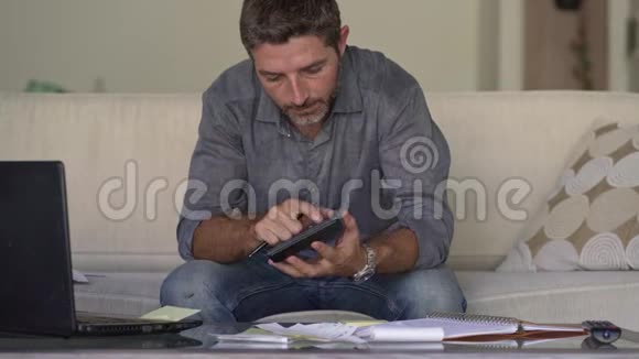 年轻有魅力忙碌的男人会用计算器计算每月的开支和债务视频的预览图