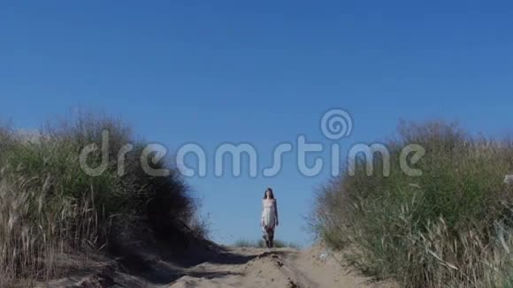 夏天穿裙子的女人走在沙滩上视频的预览图
