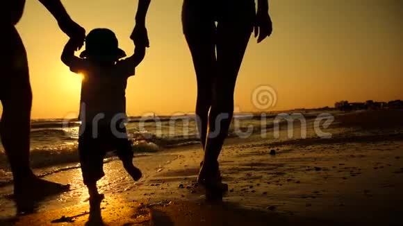 幸福的家庭在海边散步幸福的家庭和一个孩子在海滩度假剪影日落视频的预览图