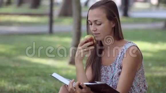 年轻女子在公园看书和吃苹果视频的预览图