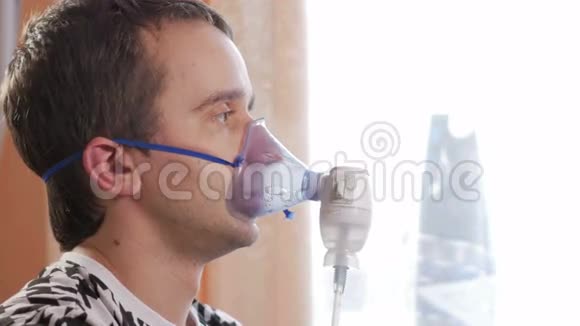在家拿着吸入器的面具的年轻人通过雾化器治疗气道炎症预防哮喘视频的预览图