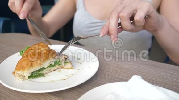 一个面目全非的女人有着漂亮的领口在咖啡馆里吃早餐还有一个羊角面包三明治里面有煮猪肉和视频的预览图