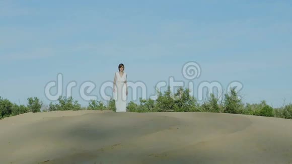 穿着白色衣服的女人在沙丘上散步视频的预览图