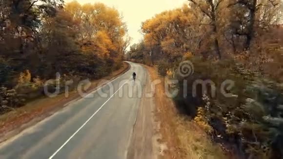 年轻的骑自行车的人骑在一条风景优美的秋天森林的路上视频的预览图