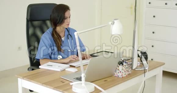 年轻的女医生坐在办公室里打字视频的预览图