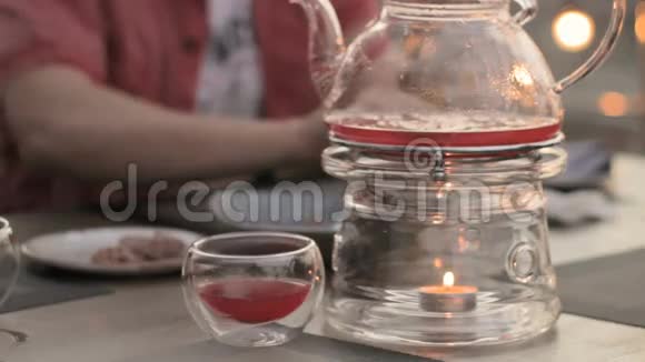咖啡馆里的人桌子上的透明茶壶和蜡烛加热视频的预览图