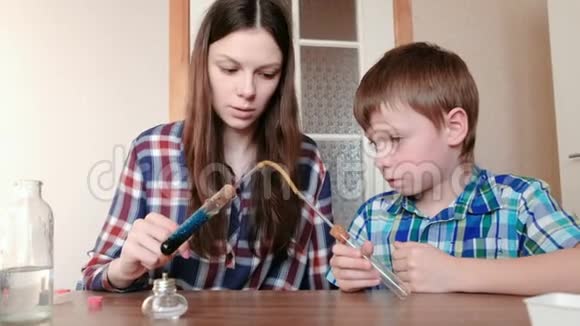 家庭化学实验男孩和他妈妈在燃烧的酒精灯上用蓝色液体加热试管这就是视频的预览图