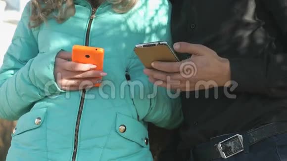 女孩和男孩站着拿着智能手机视频的预览图