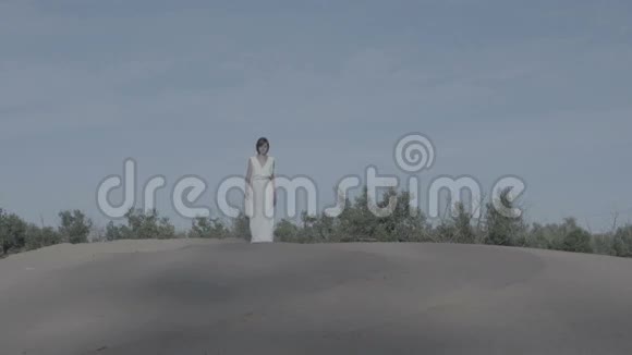 穿着白色连衣裙的女人走在没有等级的沙子上视频的预览图