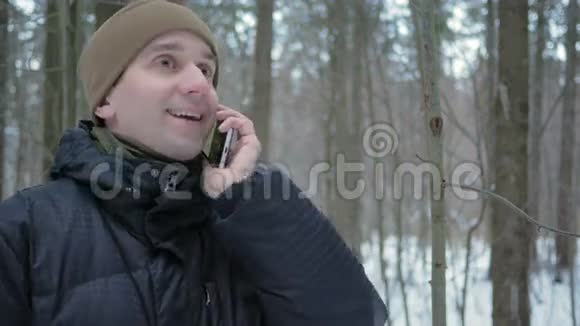 冬林一个年轻人在打电话他钦佩雪和树的两边一个穿深色夹克的男人视频的预览图