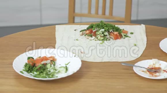 在家里的厨房桌子上煮沙瓦玛的材料皮塔蔬菜和葱配酱和视频的预览图