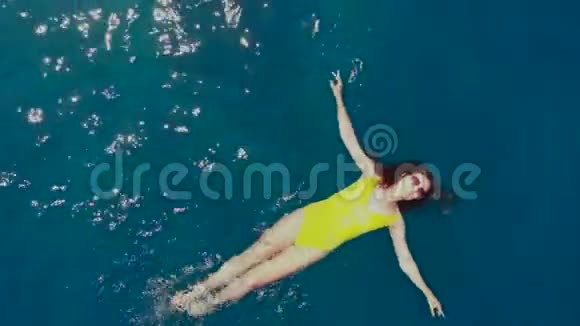 穿黄色泳衣的女孩在水里放松和游泳视频的预览图