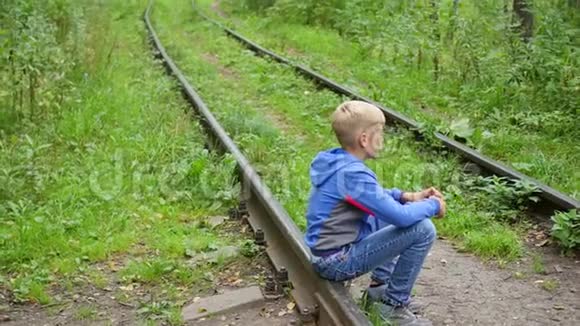 一个孤独的少年坐在铁轨上视频的预览图
