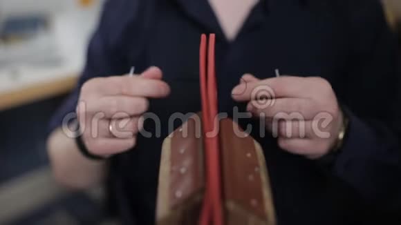 男人用自己的手在皮革车间里用一根针来制作一个棕色的皮夹特写视频的预览图