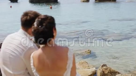 一对年轻漂亮的新婚夫妇坐在岸边视频的预览图