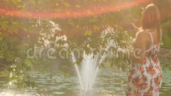 背景灯背面金发女郎照片喷泉在池塘视频的预览图