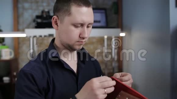 男人用自己的手在皮革车间里用一根针制造一个棕色的皮夹视频的预览图